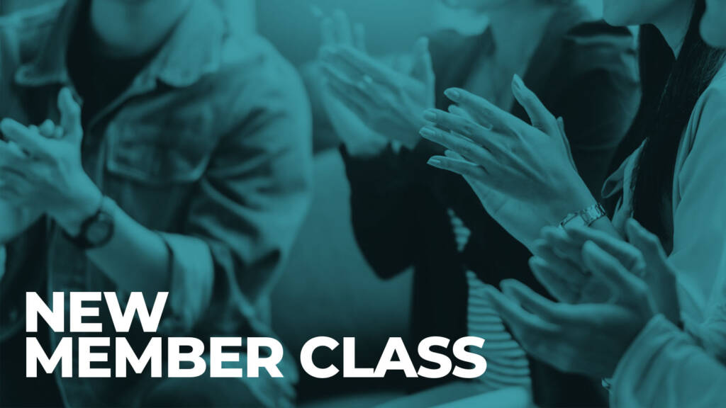 Audience applauds beneath “New Member Class” announcement
